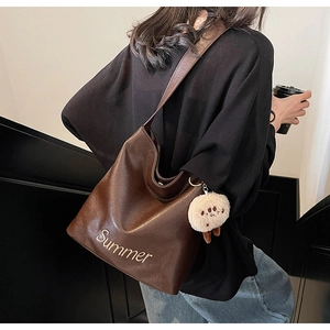Detail of dark brown tote bag with Summer print and white plush sheep keychain accessory