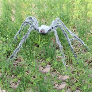 Realistic large plush Halloween spider with red eyes and poseable legs in outdoor grass