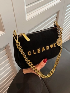Matte black crossbody bag with gold chain strap and heart letter emblem on window backdrop