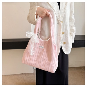 Detailed close-up of pink pleated tote bag with LOVE patch and white lace bow accessory