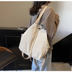 Vue latérale d'une femme portant un sac à dos en nylon blanc cassé avec cordon de serrage