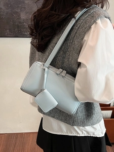 Borsa baguette in vernice azzurra con mini ciondolo indossata da una modella