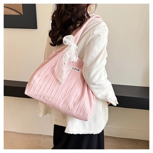 Detail of pink pleated tote bag with white lace bow and LOVE tag on model