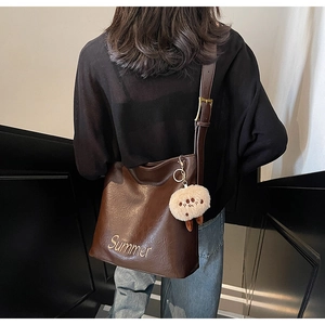 Detail view of large dark brown leather tote bag with Summer logo and plush charm