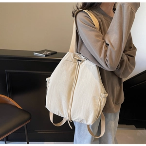 Détails du cordon de serrage et des poches latérales sur le sac à dos en nylon beige