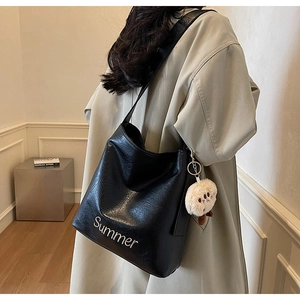 Close-up of black textured tote bag with Summer print and a white plush chick keychain