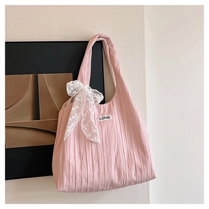 Detailed view of pink pleated tote bag featuring lace bow and embroidered love patch