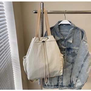 Détail du sac seau en toile blanc cassé avec fermeture à cordon et poche latérale