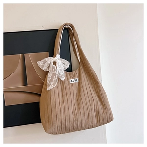 Detail of coffee brown pleated tote bag featuring lace bow and white LOVE tag decoration