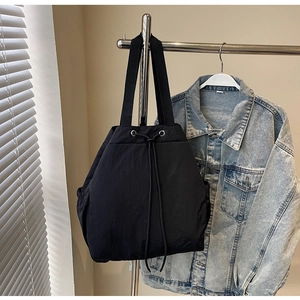 Détail d'un sac seau en nylon noir avec œillets métalliques argentés sur un cintre