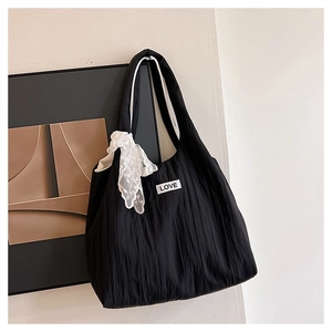 Detail of black pleated tote bag with LOVE patch and white lace bow accessory