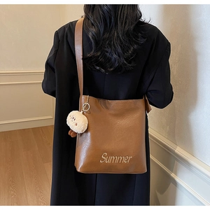 Detailed close-up of brown tote bag with Summer embroidery and cute plush bear charm