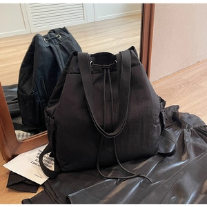 Détail du sac à dos noir en nylon avec cordon, poches latérales et texture imperméable