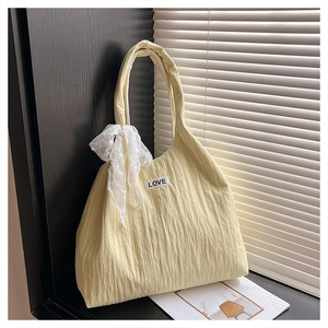 Detail of yellow pleated hobo bag with white lace bow and LOVE patch on front