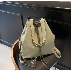 Sac à dos en nylon vert sauge avec cordon et sangles beiges sur une chaise
