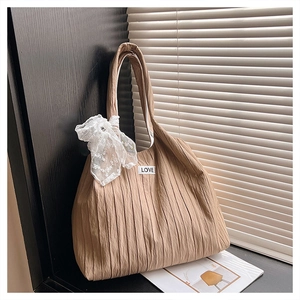 Detail of khaki pleated tote bag with white lace bow and LOVE patch in natural light