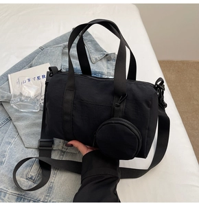 Détail du sac Boston en nylon noir avec doubles poignées et mini pochette ronde
