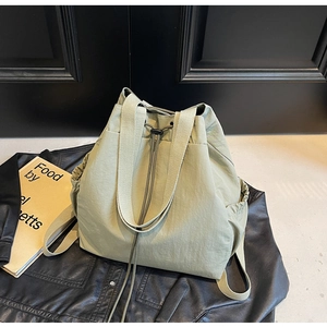Vue détaillée du sac à dos vert clair à cordon posé sur une veste en cuir