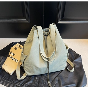 Détail du sac seau vert clair avec cordon de serrage, poches latérales et texture nylon