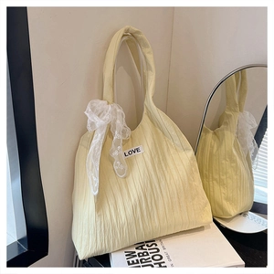 Detail of light yellow pleated tote bag with white lace bow and LOVE patch