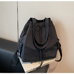 Détail du sac à dos en nylon noir à cordon avec poches latérales et texture brillante