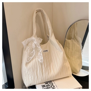 Close-up of quilted off-white tote bag featuring lace bow details and Love patch