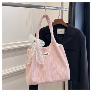 Detailed view of pink pleated tote bag with white lace bow and LOVE patch