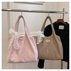 Detail view of ruched tote bags with lace bow accents and LOVE embroidery patch