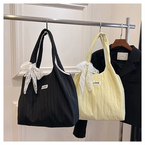 Detail of pleated tote bags with white lace bows and Love patch on a clothing rack