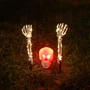 Détail de la tête de squelette d'Halloween et des mains luisantes sur la pelouse