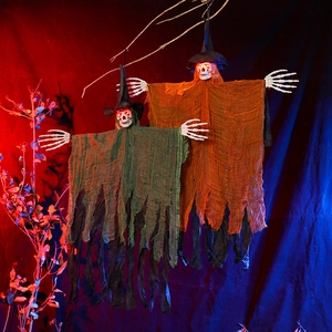 Macro detail of glowing red eyes on hanging Halloween ghosts with tattered mesh robes