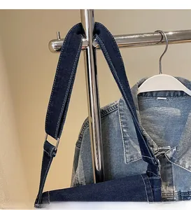 Dettaglio borsa in denim blu scuro con tracolla resistente e cuciture bianche a contrasto