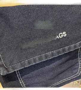 Dettaglio del tessuto denim blu scuro con cuciture bianche a contrasto e ricamo fine