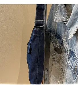 Dettaglio della borsa in denim blu scuro con fibbia in metallo argento e cuciture bianche