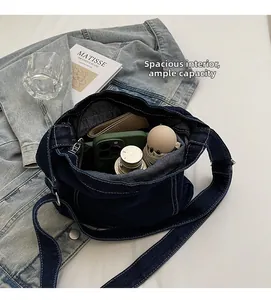 Vista dettagliata dell'ampio interno della borsa a tracolla in denim con oggetti quotidiani