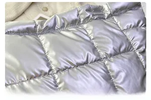 Close-up of silver quilted down fabric with metallic gloss and precision stitching