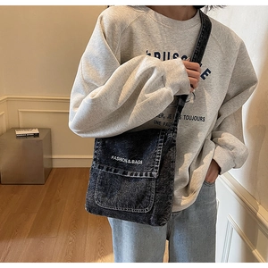 Dettaglio della borsa a tracolla in denim lavato con logo bianco e tracolla larga
