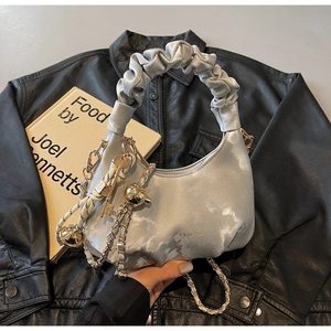 Detail view of metallic silver cloud bag with ruched texture and chain strap