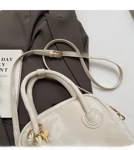 Detail of cream leather handbag with gold hardware on a stylish grey blazer suit