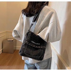 Vista posteriore della modella con borsa a tracolla in denim nero lavato con testo