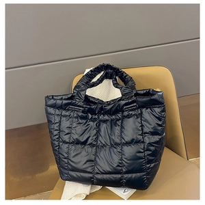 Detail of black puffer tote bag with quilted pattern and scrunchie handle on chair