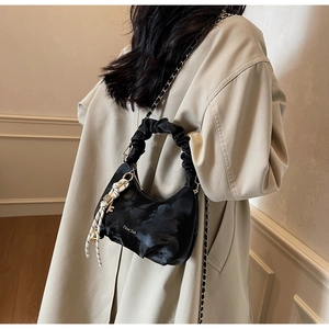 Close-up of black cloud bag with scrunchie handle and gold chain detail