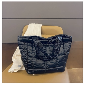 Close-up of black quilted puffer tote bag featuring glossy finish and pleated handle