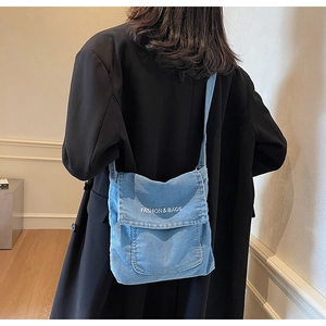 Dettaglio di borsa a tracolla vintage in denim blu indossata con un blazer nero