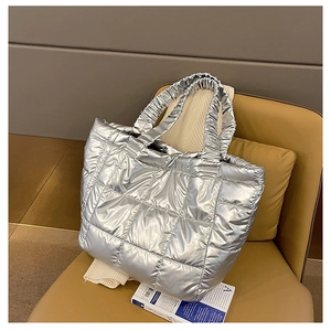 Detail of silver quilted tote bag featuring metallic finish and ruffled handle design