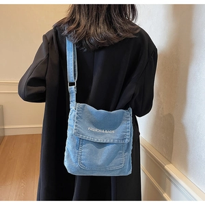 Vista posteriore dettagliata di una borsa a tracolla in denim blu con testo bianco sulla patta