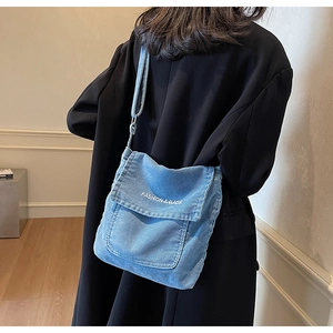 Dettaglio della borsa a tracolla in denim blu con stampa bianca e tracolla regolabile