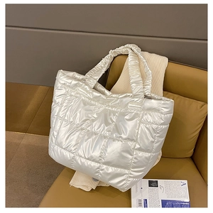 Detail of white quilted puffer tote bag with ruched handles on a brown leather chair