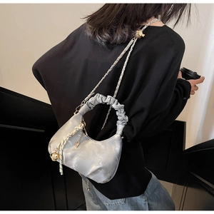 Detail of silver pleated cloud bag featuring golden chain strap and brand logo