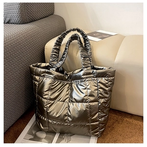 Macro detail of bronze metallic quilted tote bag featuring elastic ruched handles and finish